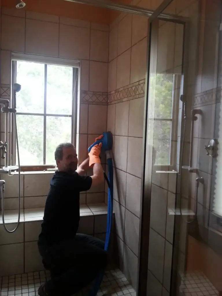 Technician cleaning tile and grout in residential shower in Summit County Colorado