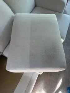 A light gray herringbone upholstered sofa cushion showing visible soiling and discoloration before professional upholstery cleaning in Frisco, CO.