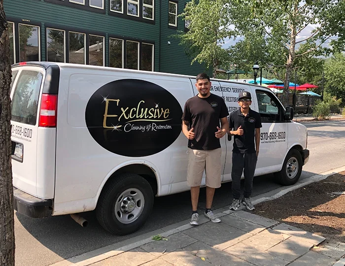 Exclusive Cleaning and Restoration certified technicians standing in front of the Exclusive Cleaning van while working on carpet cleaning in Breckenridge.